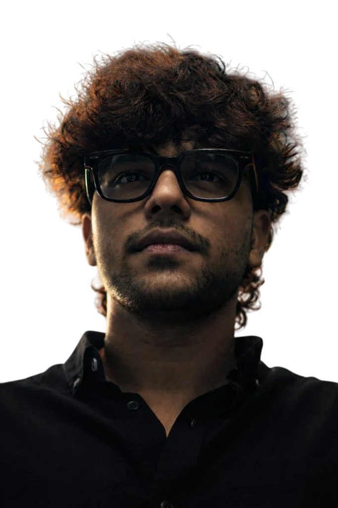 “Portrait of a man with curly hair and glasses wearing a black shirt”